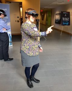 Photo of a person eewearing a Microsoft Hololens display and pointing with one finger